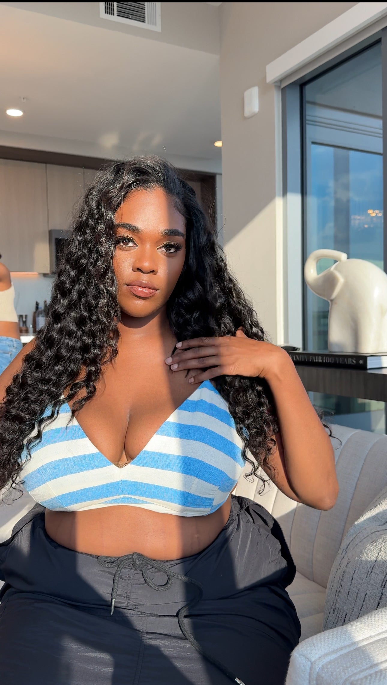 Woman in a blue and white striped top sitting with loose curly clip ins.