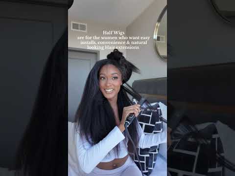 Smiling Black woman in white crop top straightening her styled clip-in hair extensions 