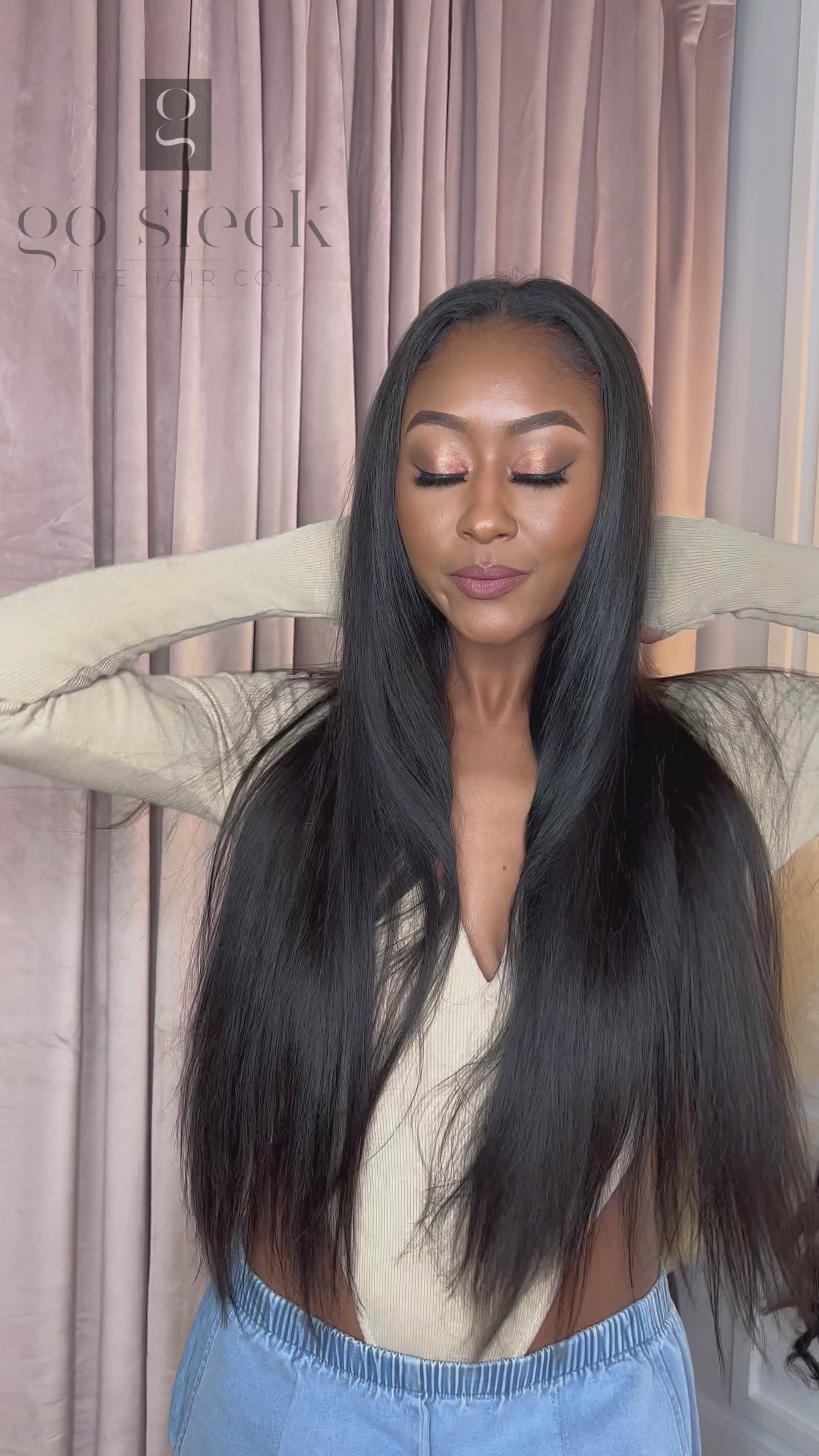 Woman in a light brown bodysuit playing with her “Venus” Body Wave Seamless Clip-Ins, showing off the natural movement, volume, and soft wave pattern of the 100% Virgin Human Hair extensions.