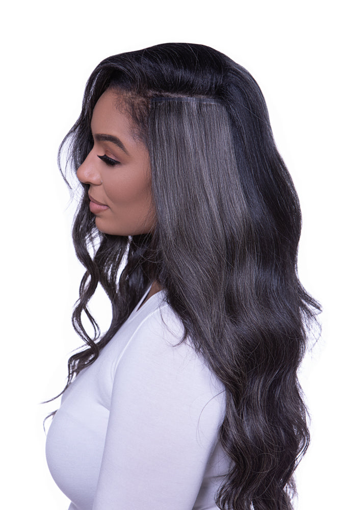 A woman with gray hair featuring clip-in hair extensions that are blends of dark brown and beige hues.
