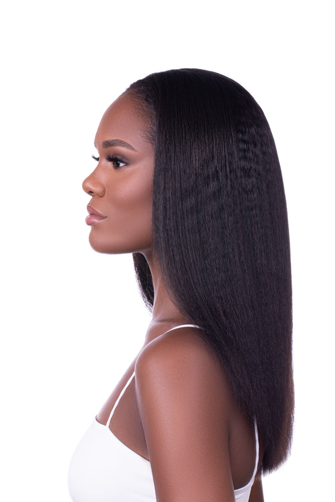 Side profile of a woman wearing Go Sleek Seamless Kinky Straight Clip-In Hair Extensions, styled in a sleek, natural texture that mimics blow-dried natural hair. She’s wearing a white tank top against a white background.